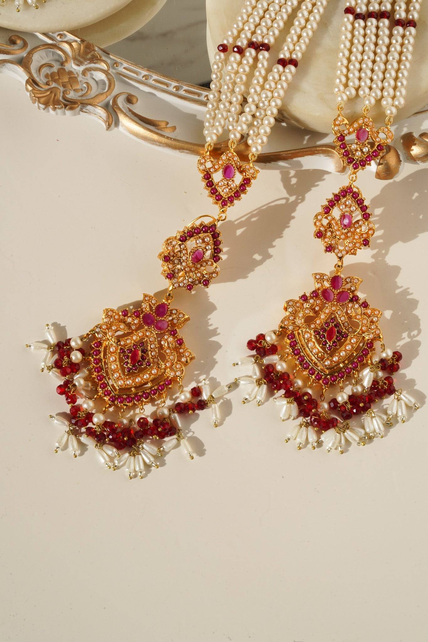 Red stone Sanjana Jewelry Set with gold detailing and pearl drops, blending Indian and Pakistani jewelry traditions.