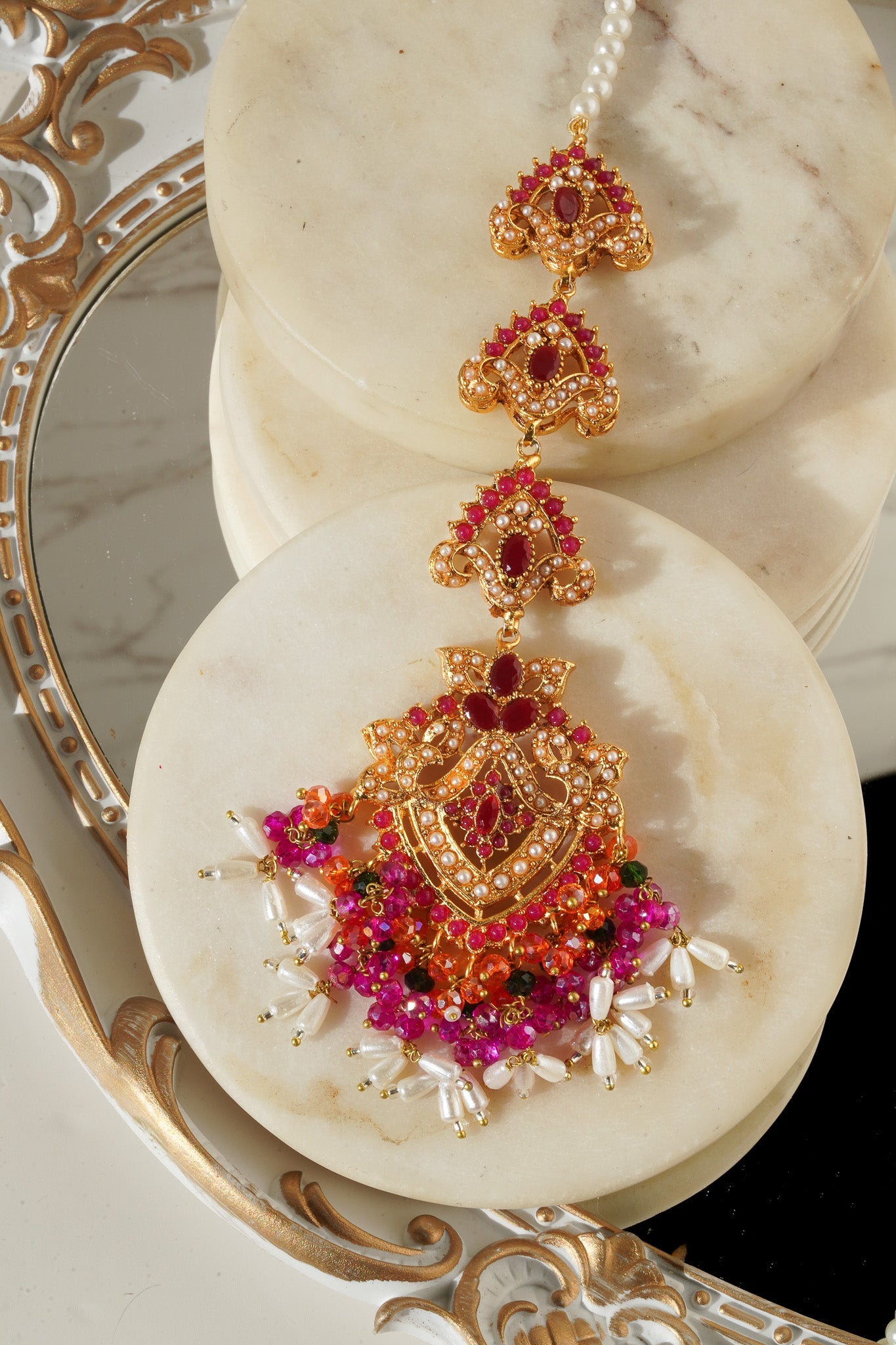 Sanjana Earrings and Maang Tikka Set in pink and green with pearl strands, perfect for weddings and traditional events.