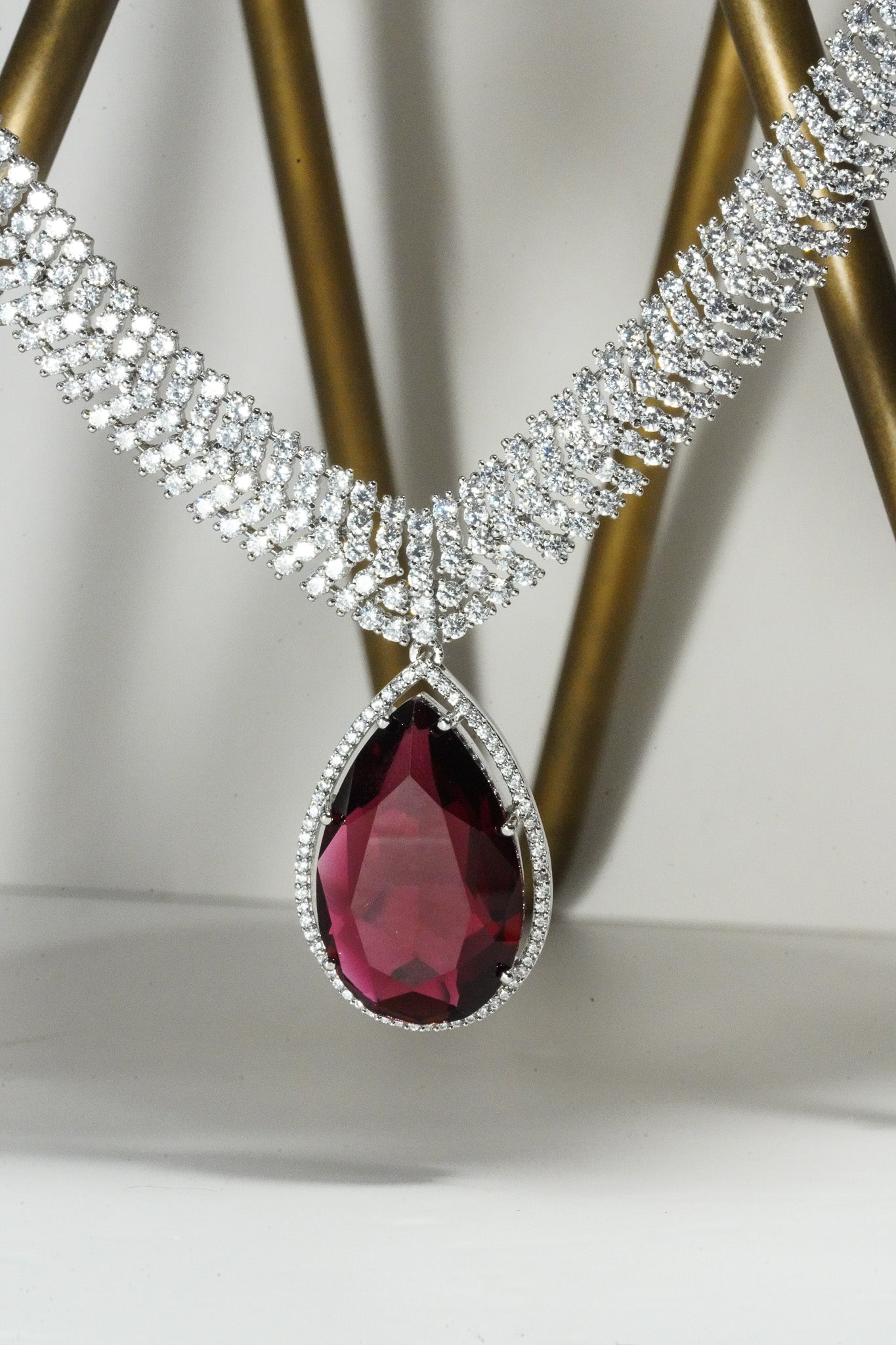 Sharmine Paved Silver Diamanté Accent Necklace Set - Rhodium-plated with Diamanté stones, featuring a large teardrop stone and chandelier earrings, available in multiple color options, perfect for modern South Asian ensembles.