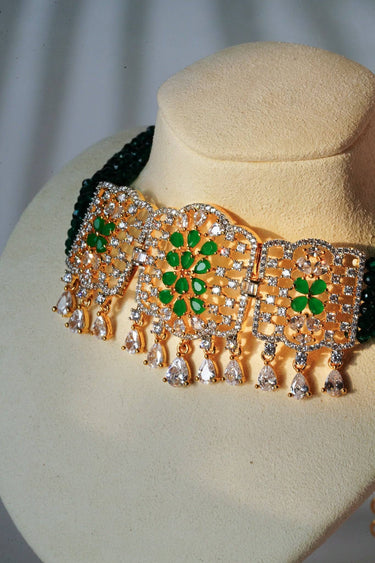 Close-up of Sumra Gold & Pearl Choker Necklace Set with green floral design and cubic zirconia. Elegant jewelry for weddings or events.