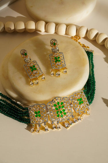 Sumra Gold & Pearl Choker Necklace Set with green accents and cubic zirconia, laid flat with matching earrings. Perfect for festive wear.