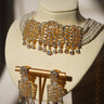 Sumra Gold & Pearl Choker Necklace Set with cubic zirconia and faux pearls, displayed on a bust with matching earrings. Elegant jewelry for occasions.